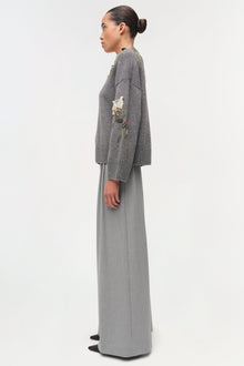 Gray knit sweater with floral embroidery on sleeve, worn with gray maxi skirt.