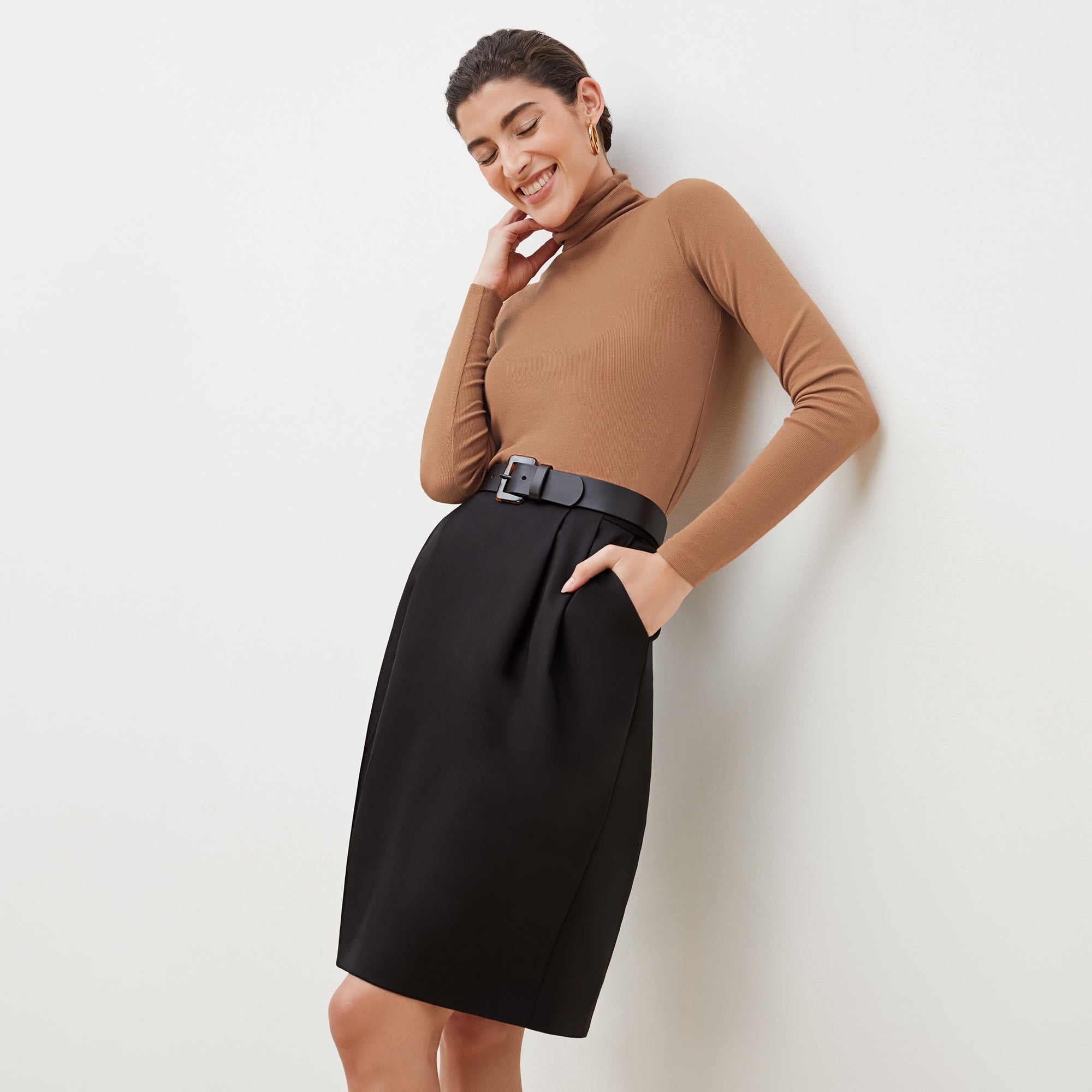 Front image of a woman standing wearing the axam top in camel | Exclude