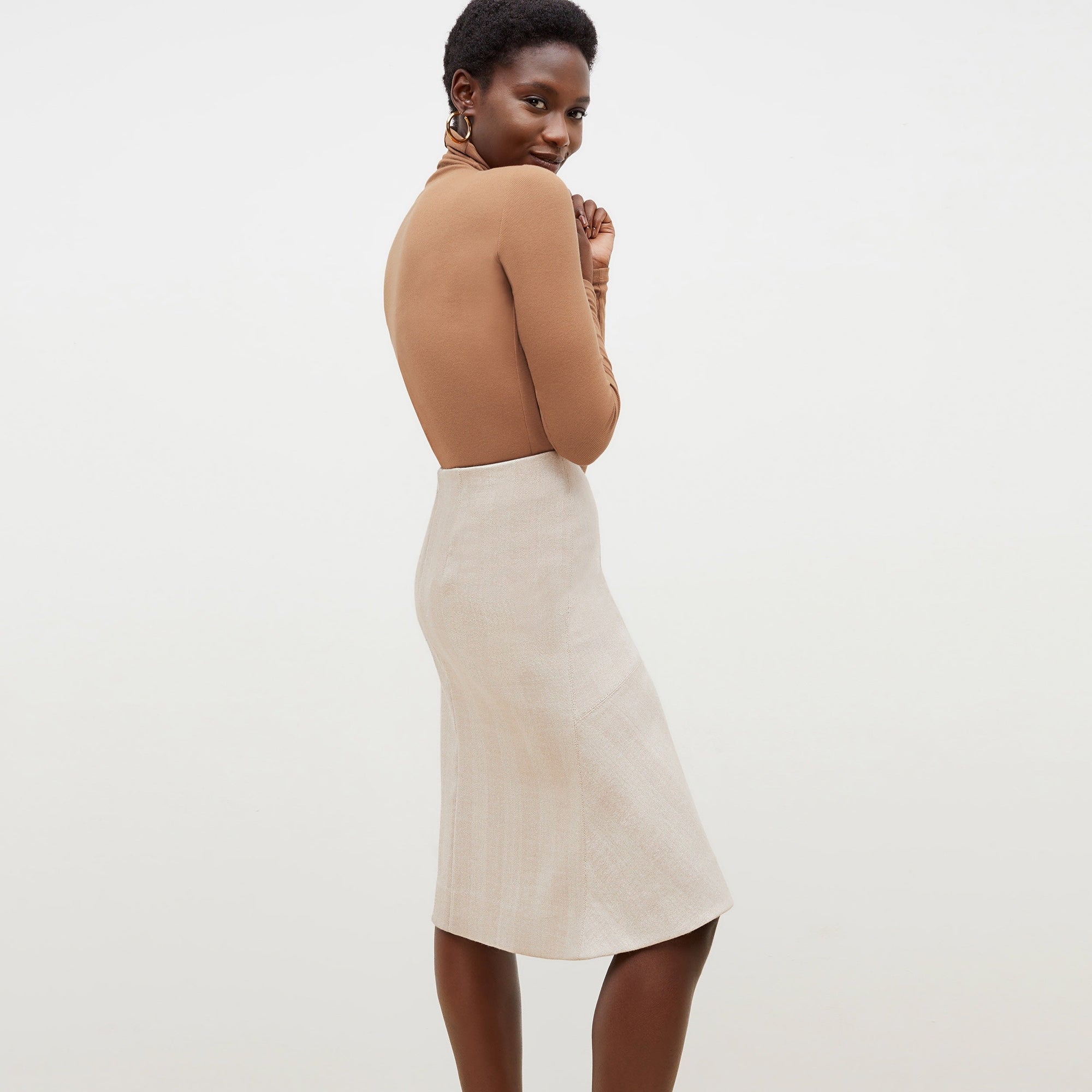 Back image of a woman standing wearing the axam top in camel | Exclude