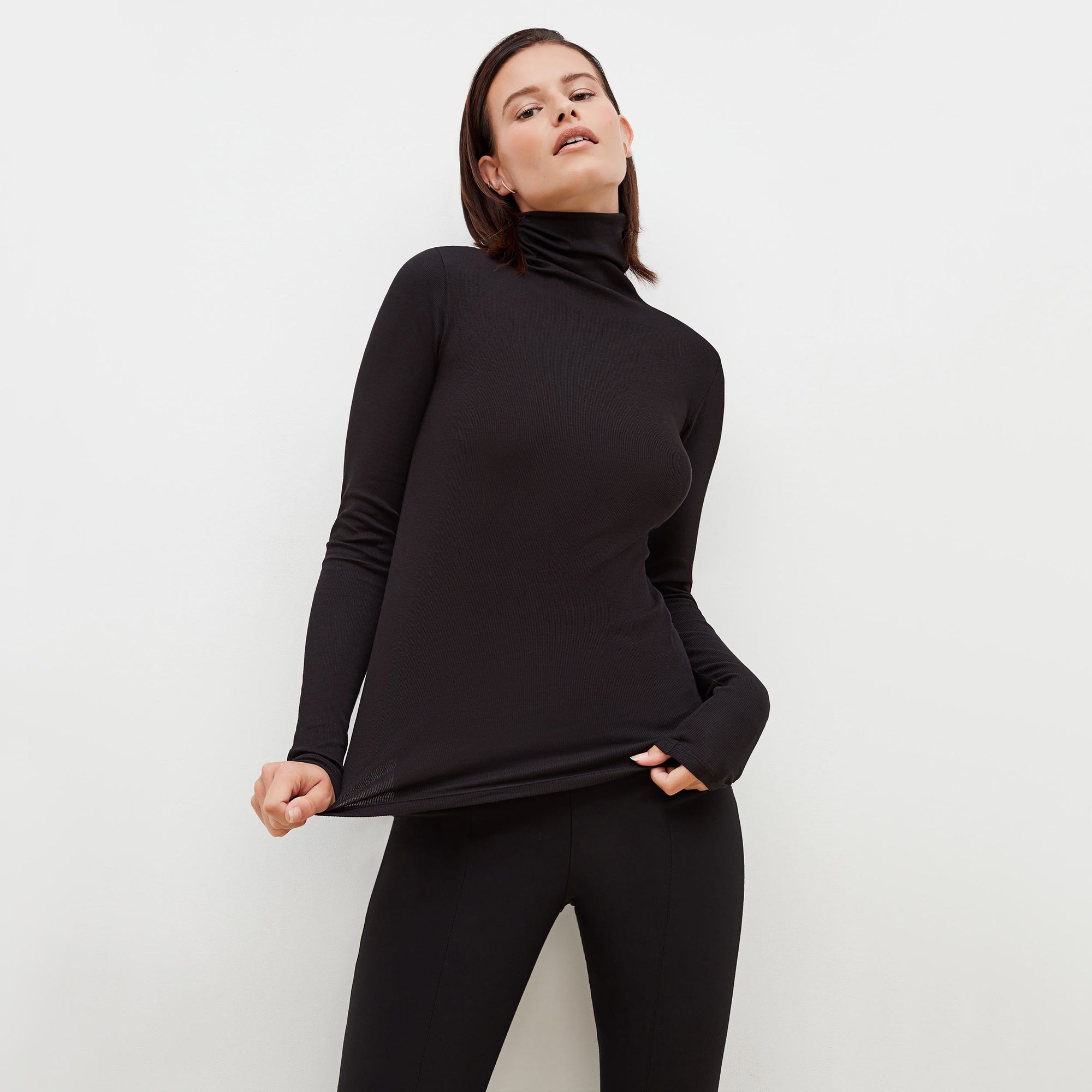 Front image of a woman standing wearing the axam top in black