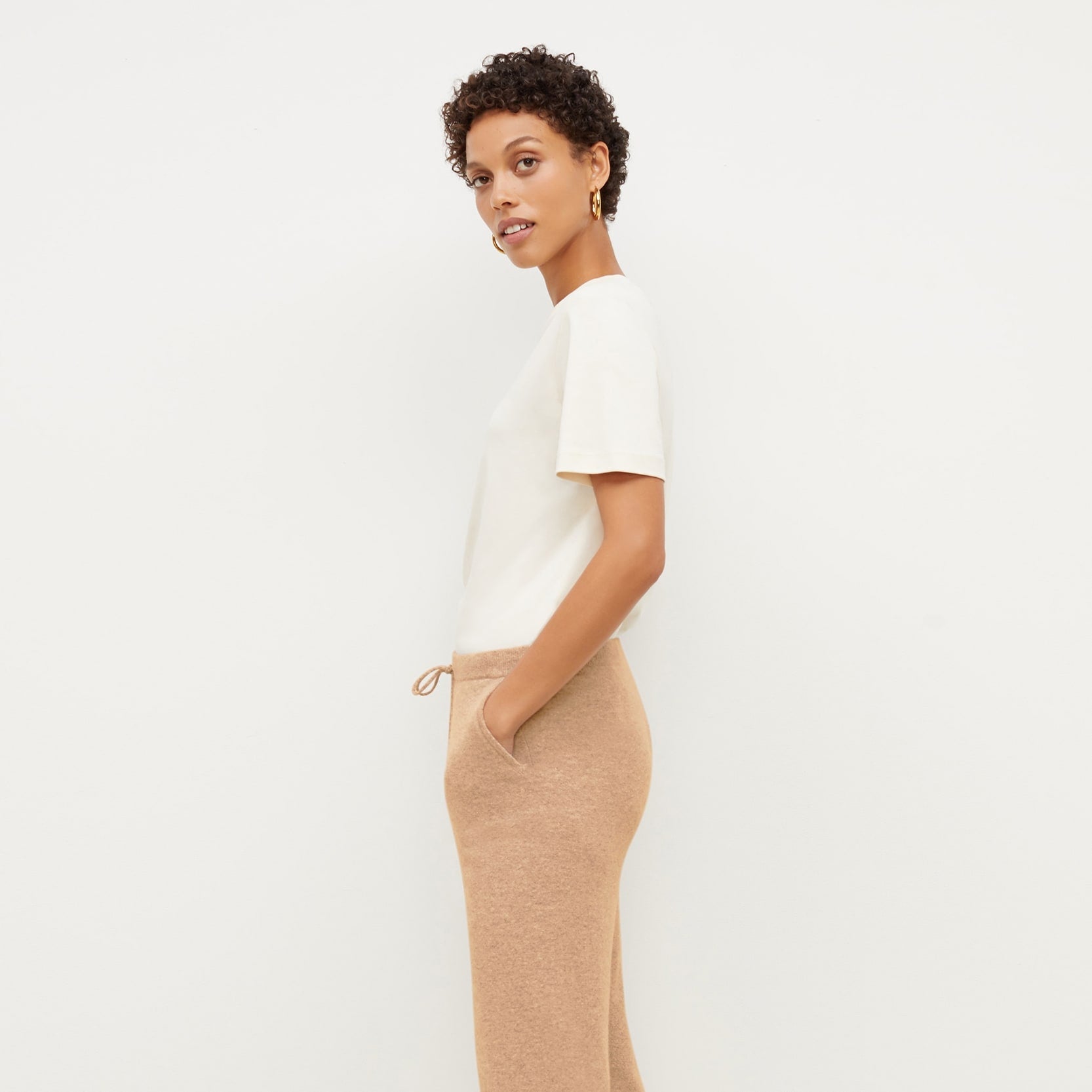 Side image of a woman standing wearing the leslie top in compact cotton in ivory | Exclude