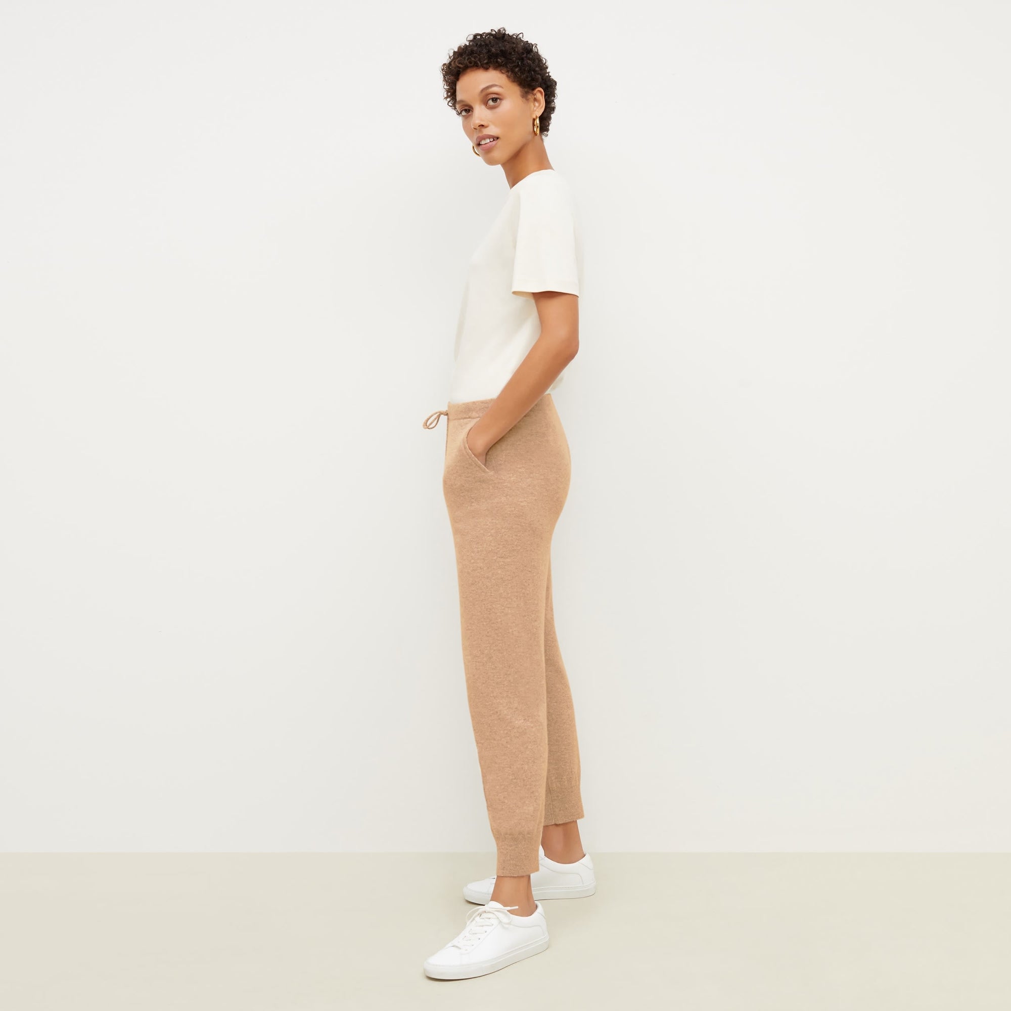 Side image of a woman standing wearing the leslie top in compact cotton in ivory | Exclude