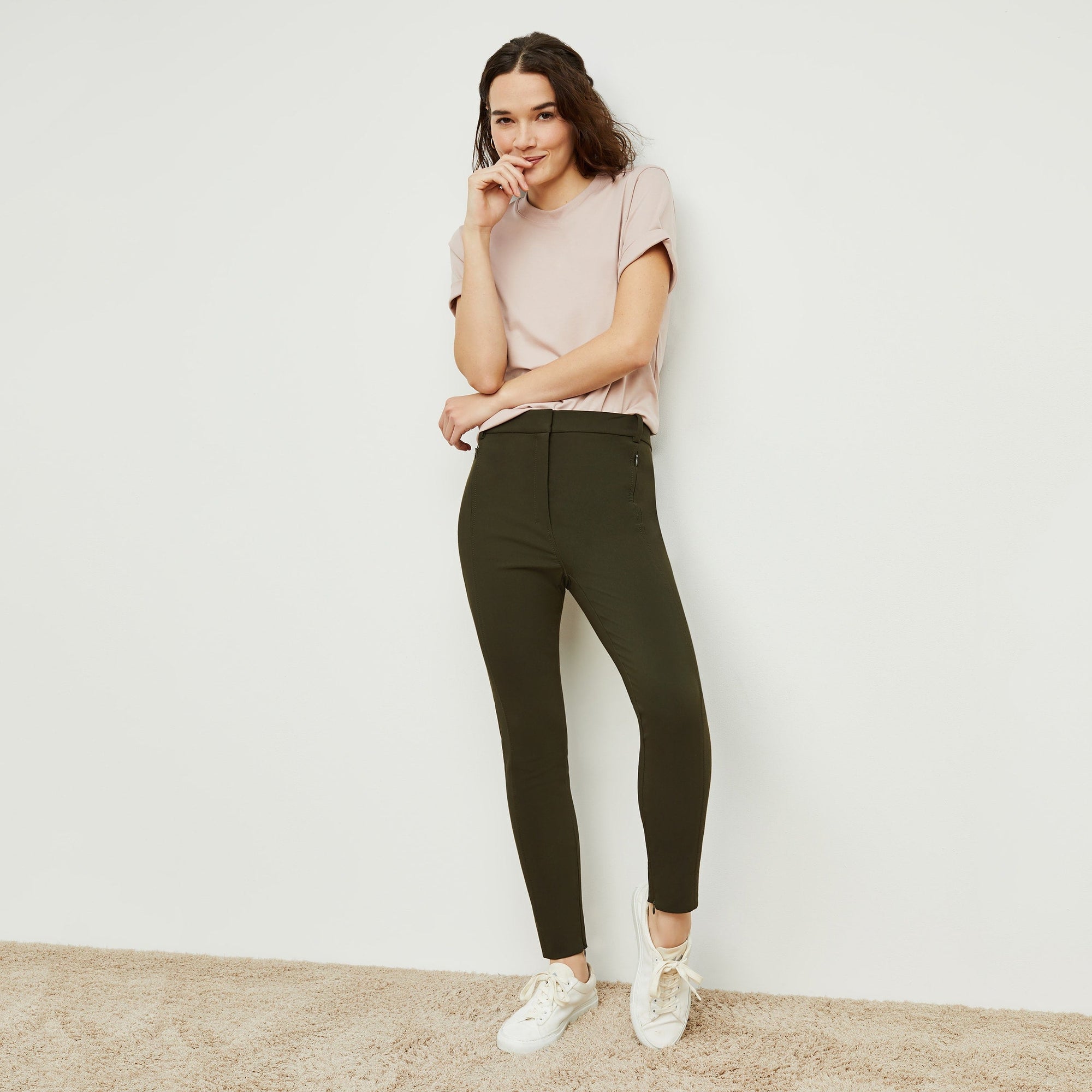 Front image of a woman standing wearing the curie pant in dark olive | Exclude