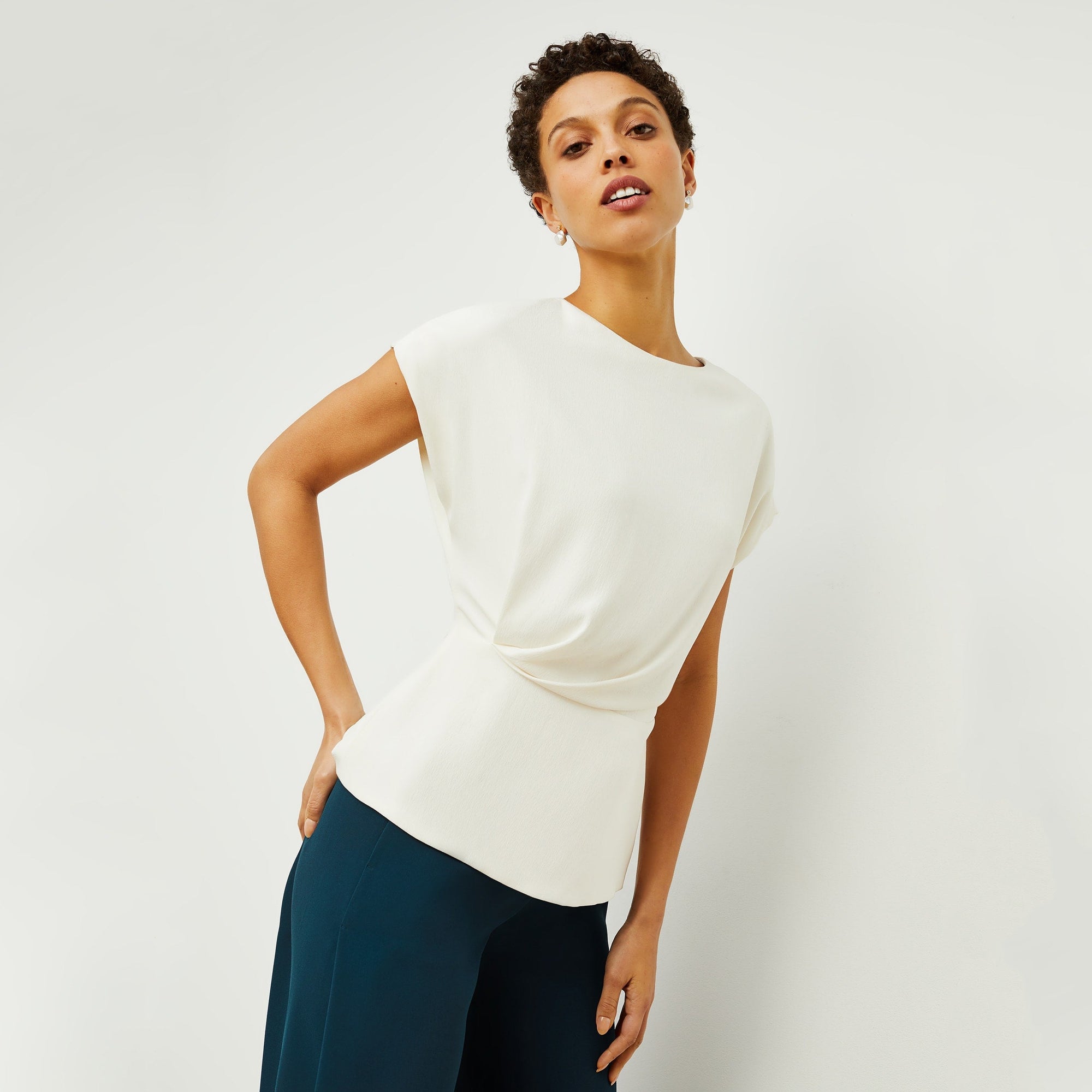 Side image of a woman standing wearing the Nejvi Top in alabaster | Lead