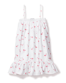 The Girls Twill Lily Nightgown in Flamingos by Petite Plume blends summer charm and cotton comfort. This white sundress features thin straps, a playful pink flamingo pattern, a ruffled hem, and a textured band near the neckline for a breezy yet cozy feel.