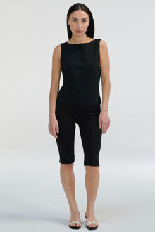 Woman wearing a black sleeveless top and black capri pants on a white background