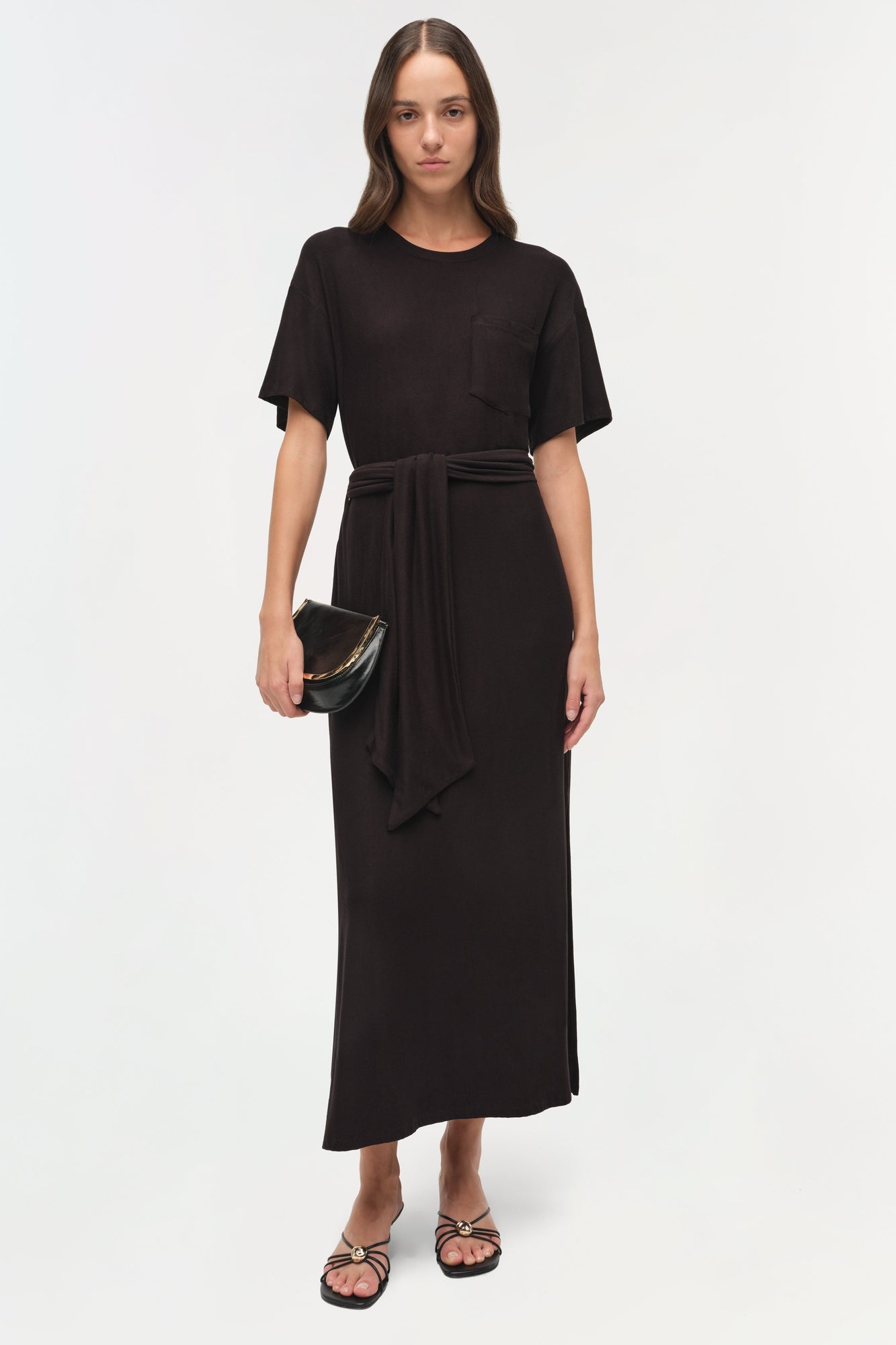Black jersey t-shirt dress with short sleeves, chest pocket, and tied waist detail.