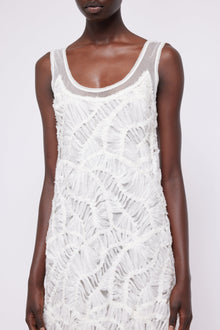 White sleeveless dress with scoop neckline and diagonal fringe texture throughout.
