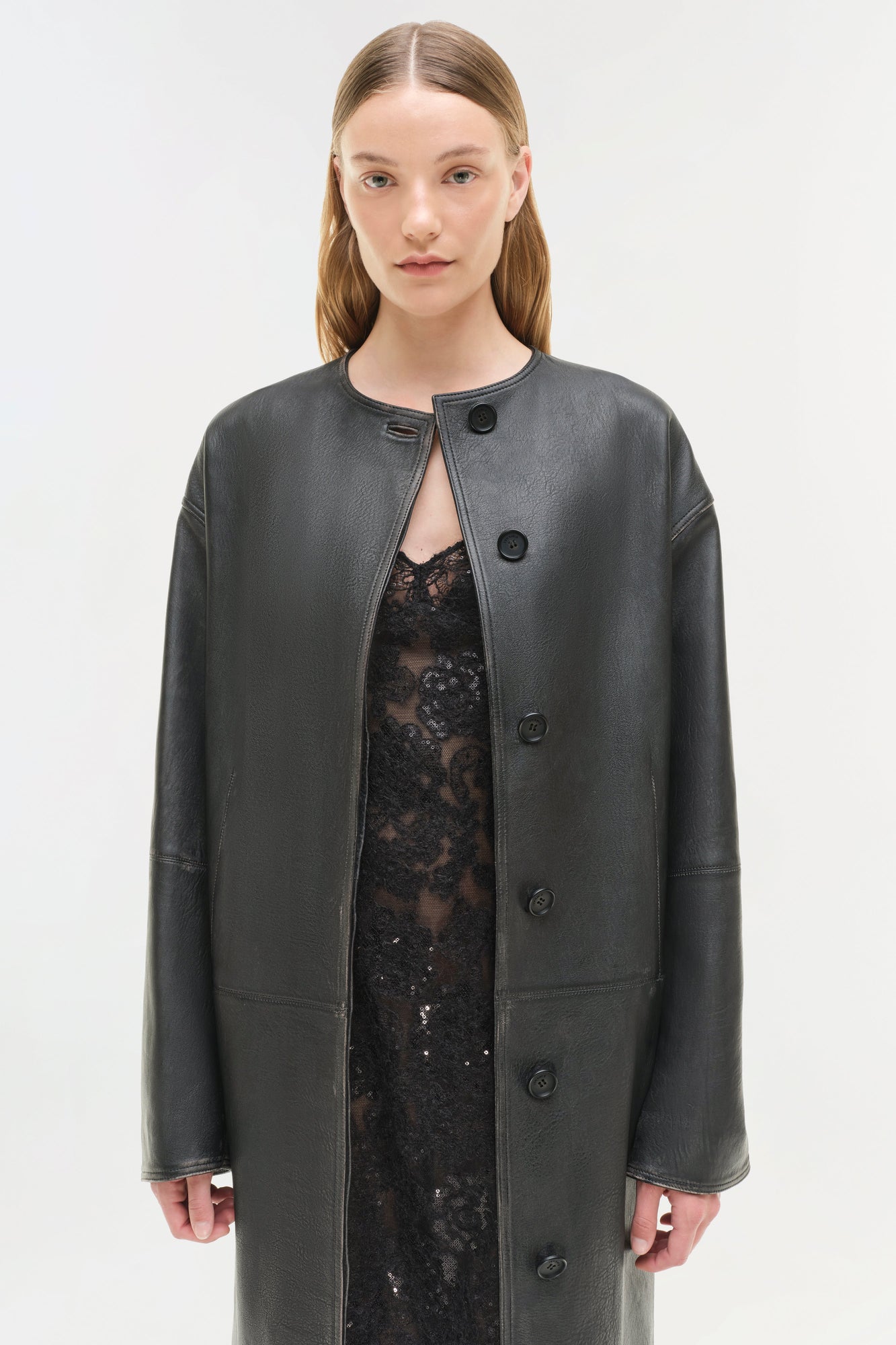 Dark gray leather jacket with button front closure, worn open over a black lace top.