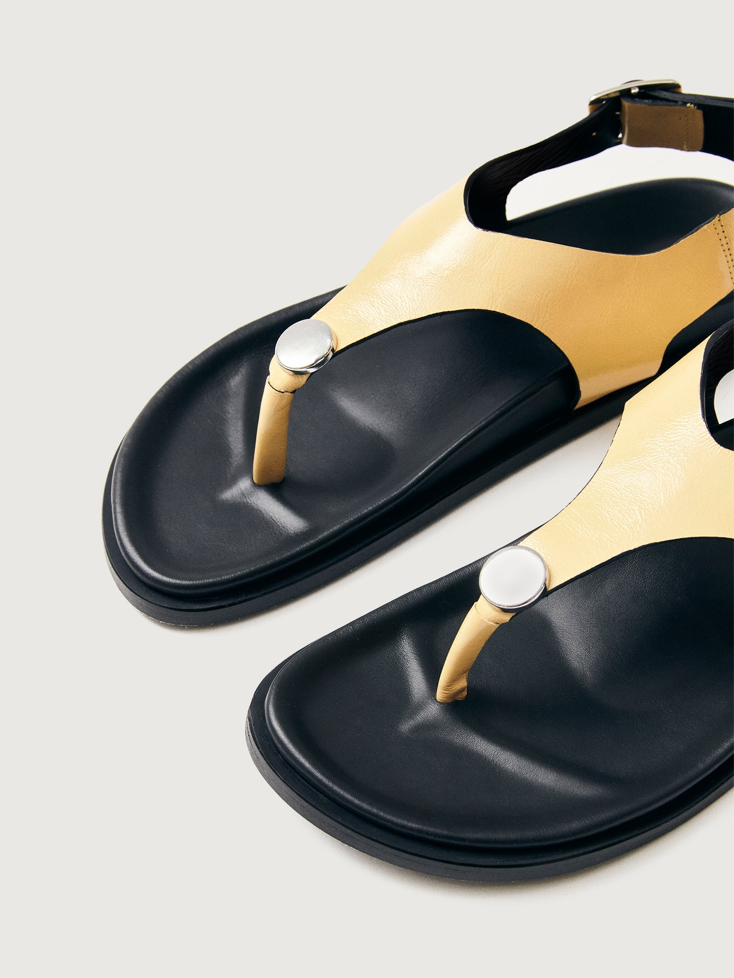 Buttery yellow colored sandal with black sole and silver hardware. 