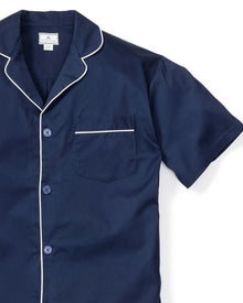 The Mens Twill Pajama Short Set in Navy by Petite Plume is a classic luxury piece featuring a navy short-sleeve top with white buttons, piping, collar, and left chest pocket. Made from 100% cotton, it combines comfort and style for a restful night.