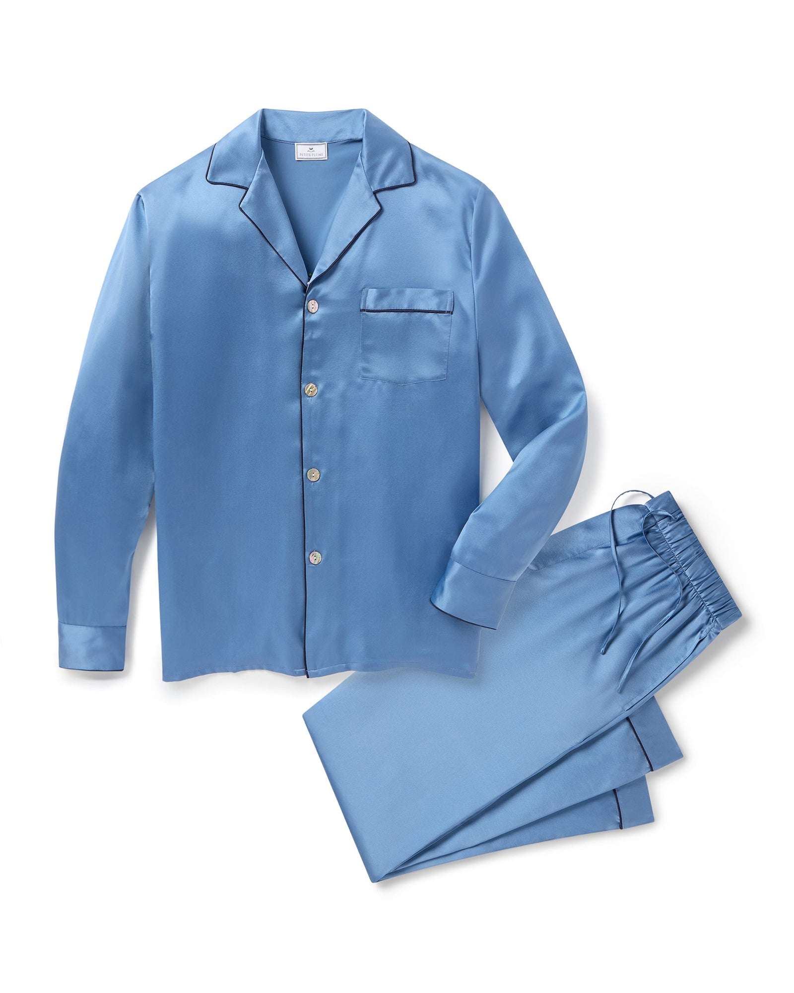 The Men's Silk Pajama Set in Mystique Blue features a button-up long-sleeve top with a chest pocket and matching elastic-waist pants, both trimmed with dark piping.