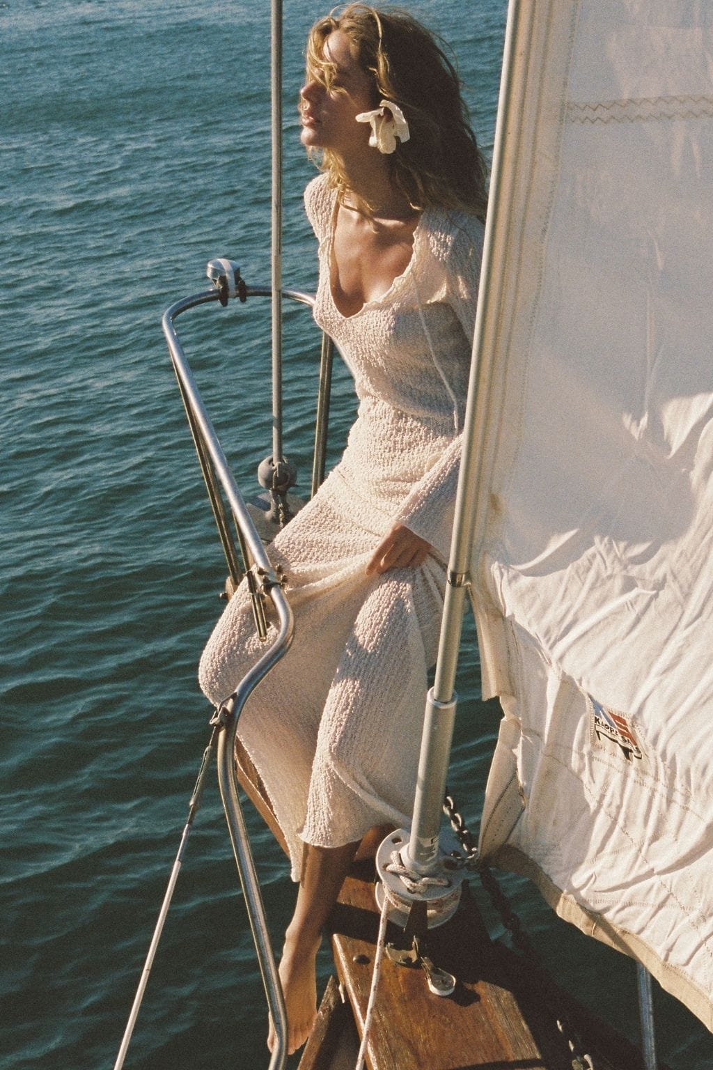 Woman wearing cream textured long dress with flared skirt on sailboat.