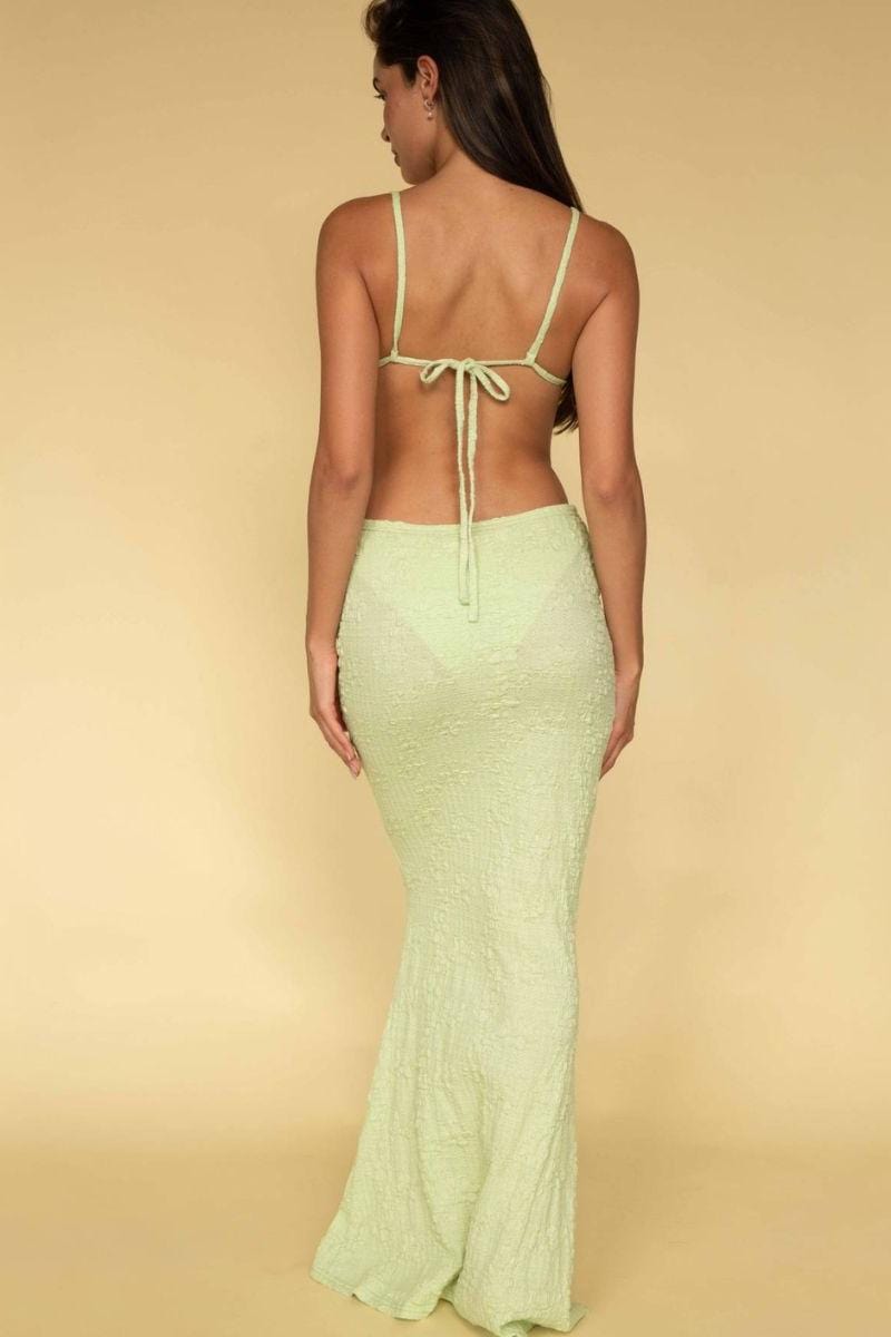 Woman wearing pale green textured maxi skirt with matching tie-back bikini top, shown from behind.
