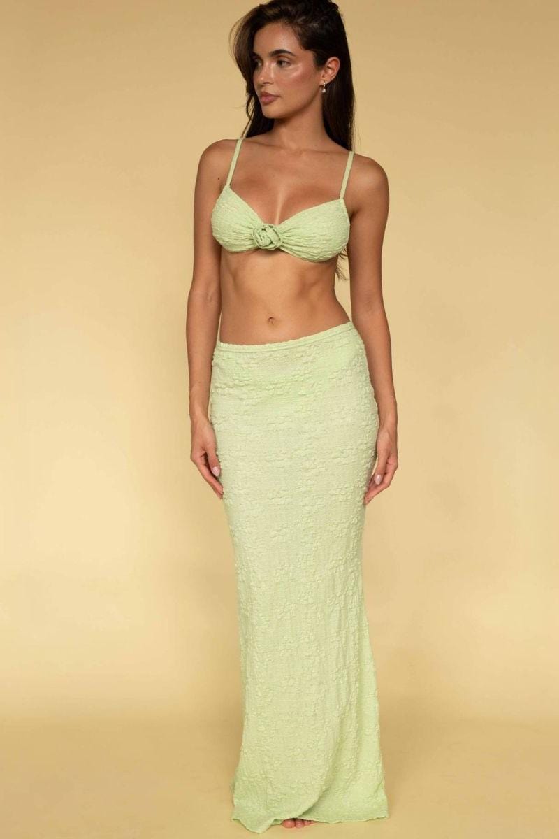 Woman wearing light green textured maxi skirt with matching bikini top tied at center front.