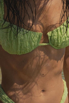 Lime green bikini top with textured petal-shaped cups on model shown from front.
