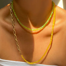 Shimmering beaded necklace made of smooth opals in shades of yellow on a gold linking ovals clasp
Styled on a neck layered with a green opal necklace and chain necklace. 