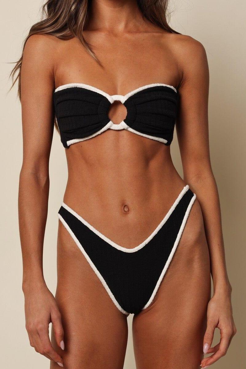Black thong bikini bottom with cream-colored binding and textured terry rib fabric.