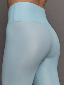 Model wears a pair of high rise baby blue sleek liquidy shine leggings. 