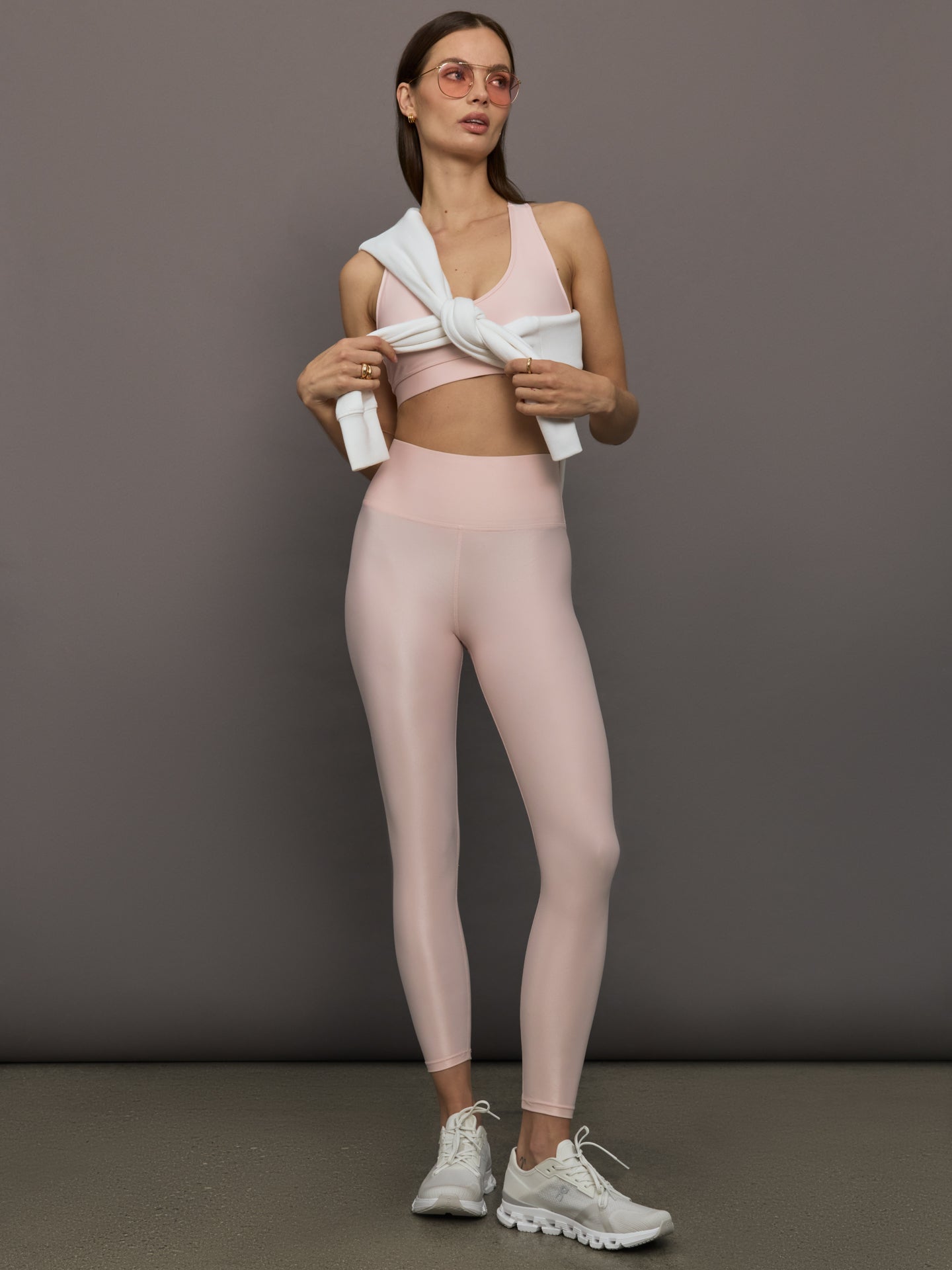 Model wears a pair of high rise baby pink sleek liquidy shine leggings. 