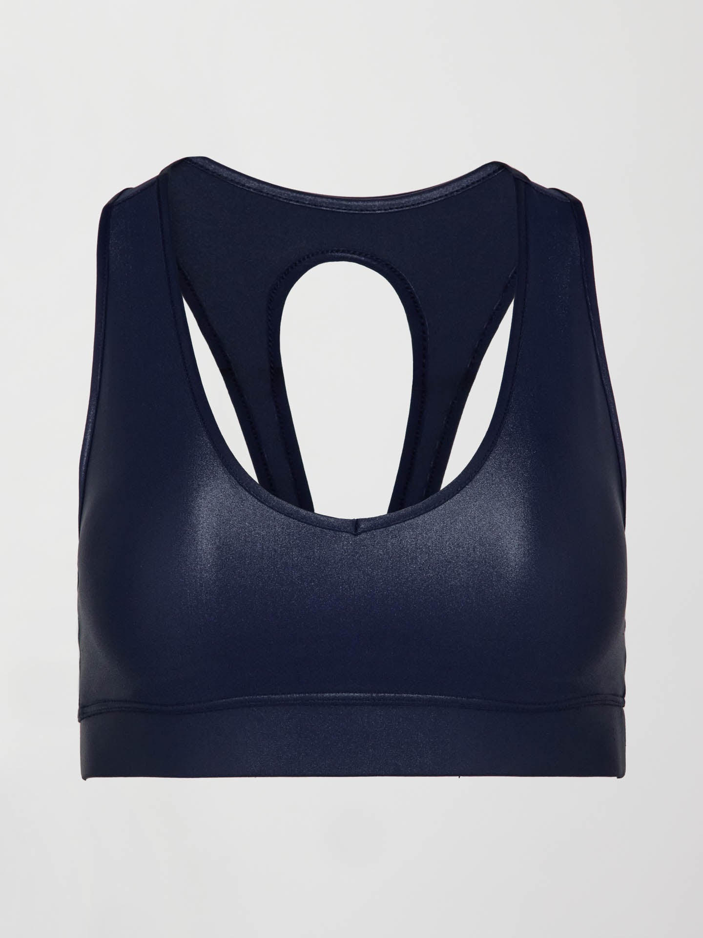 Model wears a navy, glossy, deep scoop-neck sports bra with a sleek racerback and a shiny, liquid-like finish.

