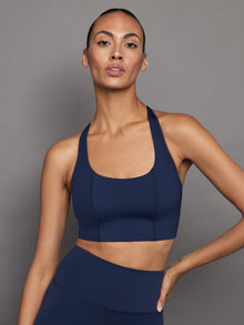 Model wearing navy compression sports bra, front view.