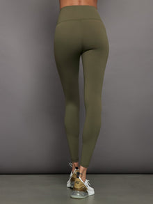 Model wears full-length olive leggings with a high-rise wide waistband and smooth, compressive fabric.