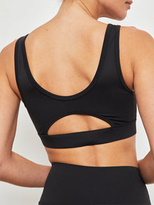 Back view of black cut out scoop sports bra showing open back detail.