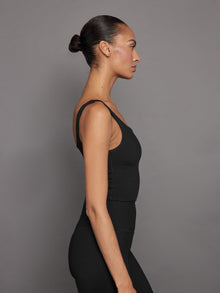 Side profile of model wearing ribbed black cropped tank top.