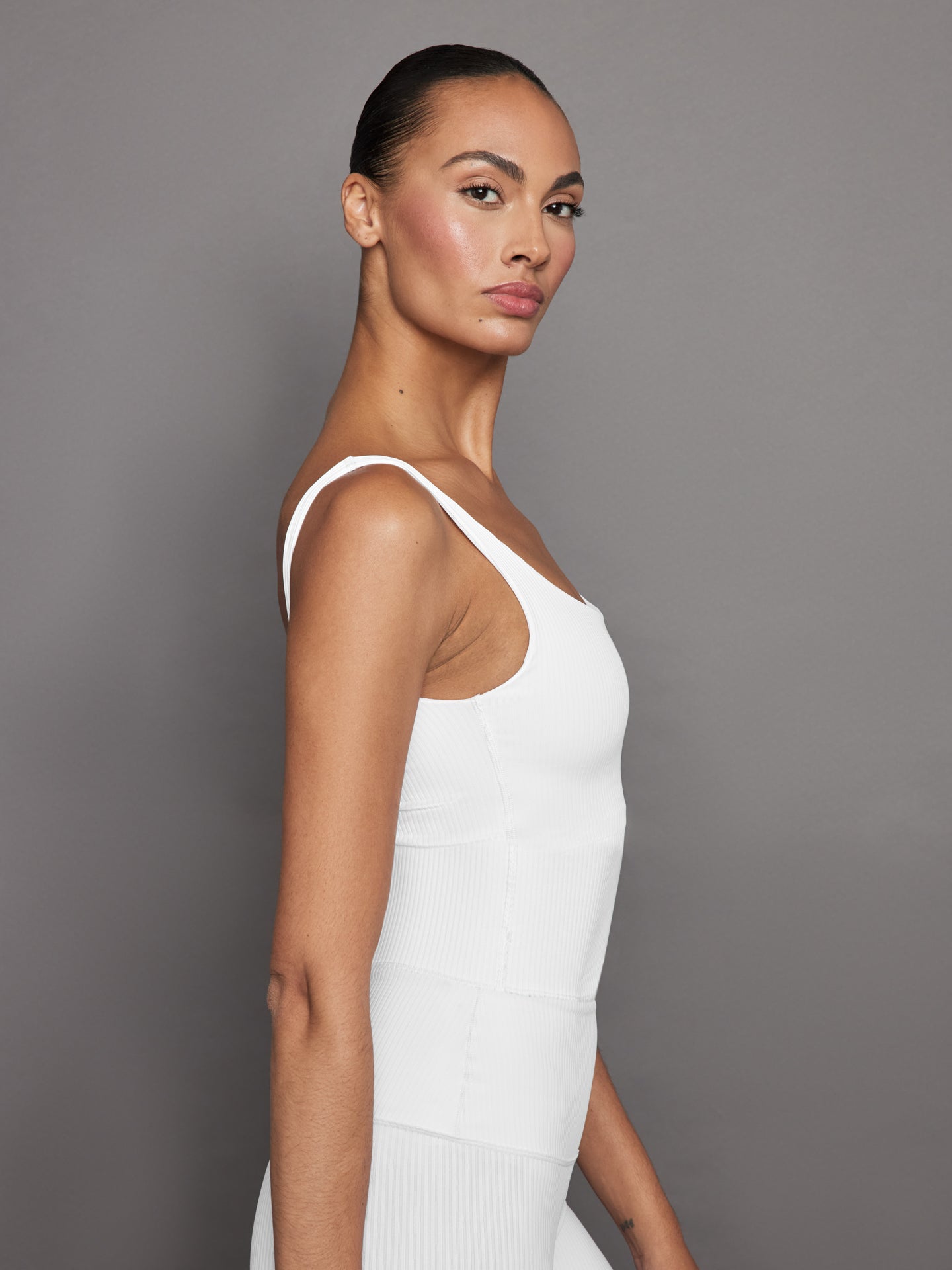 Side profile of model in white ribbed crop tank highlighting fit.