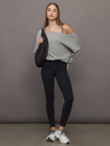 Model styled in Melt High Rise Sport Pocket Legging Black with gray oversized sweater and crossbody bag.