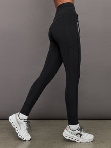 Side view of Melt High Rise Sport Pocket Legging Black on model with white sneakers.