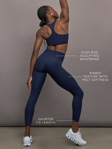 Model wears navy, high-rise leggings with a ribbed texture and a smooth, form-fitting silhouette.
