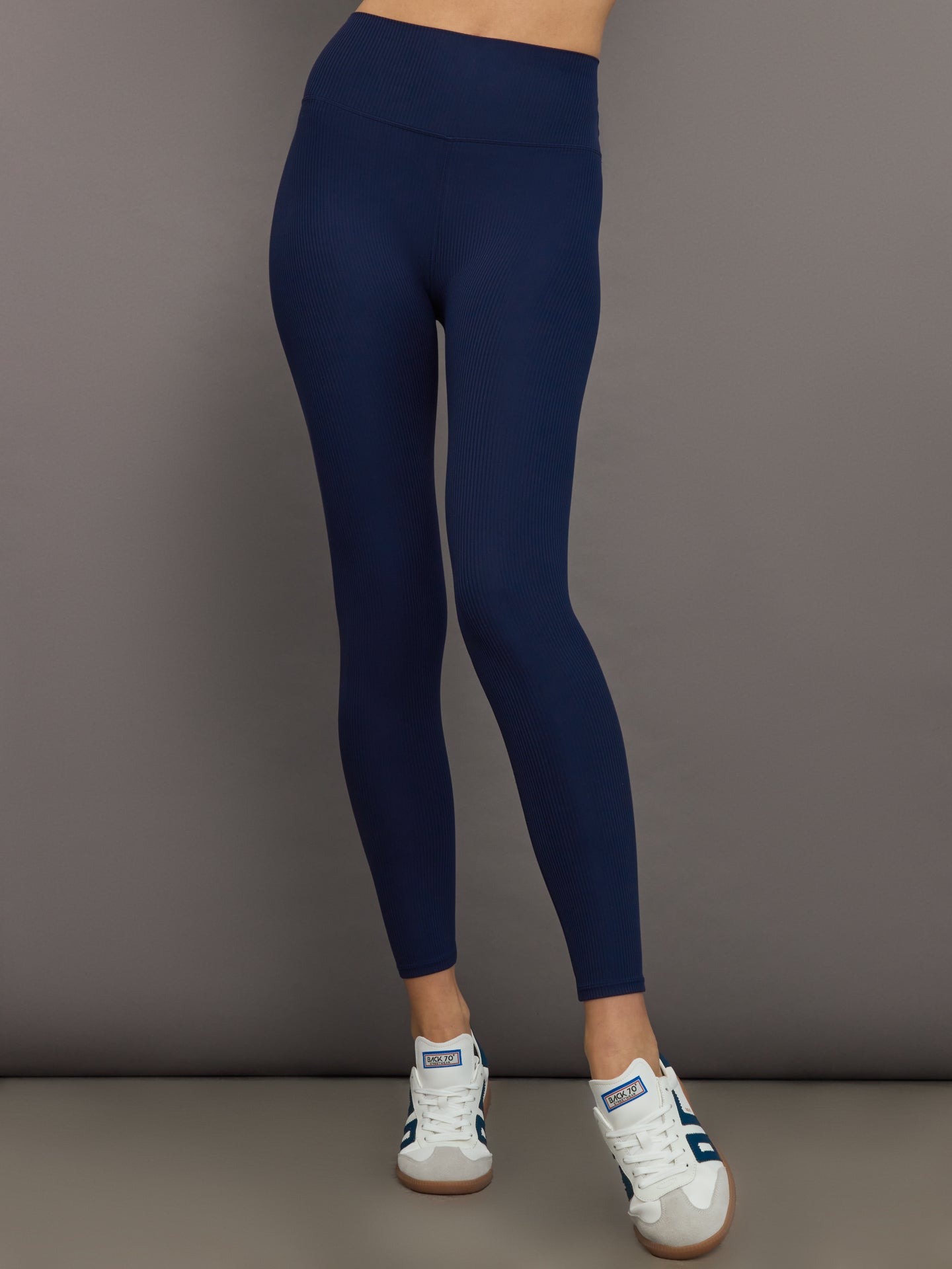 Model wears navy, high-rise leggings with a ribbed texture and a smooth, form-fitting silhouette.
