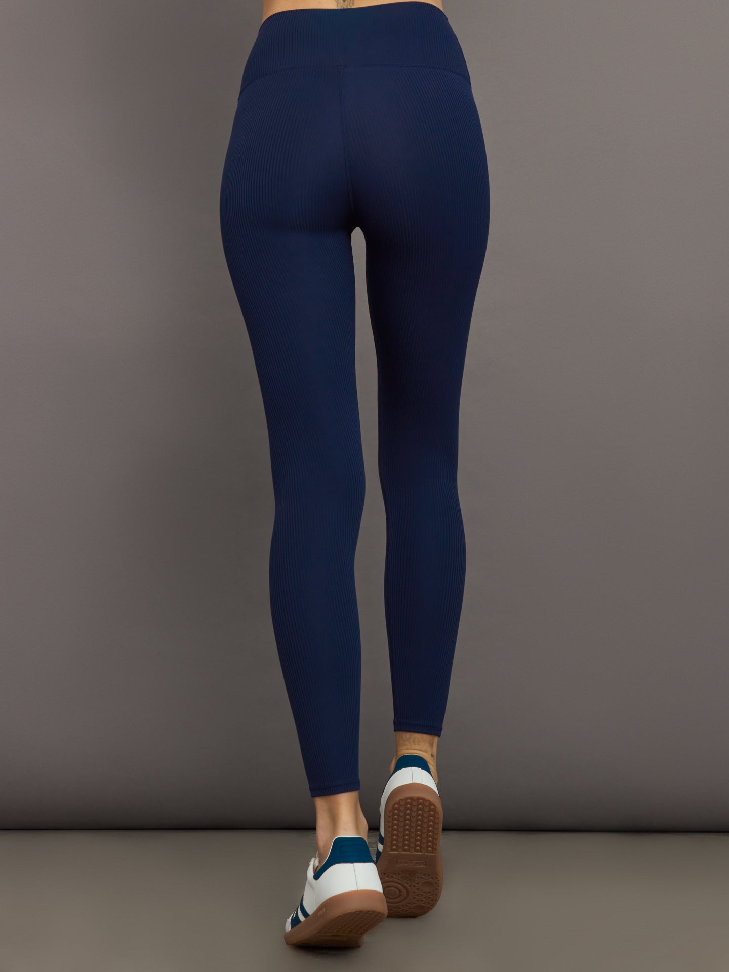 Model wears navy, high-rise leggings with a ribbed texture and a smooth, form-fitting silhouette.
