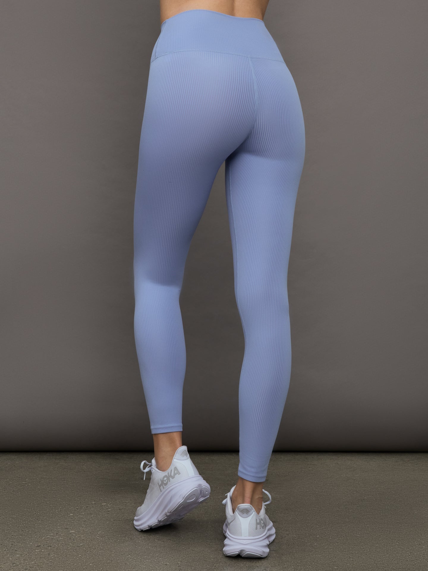 Model wears a pair of high waisted periwinkle colored ribbed leggings. 