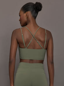 Model wears a buttery soft sports bra in army green with double straps and cross back design. 
