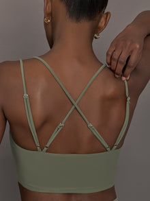 Model wears a buttery soft sports bra in army green with double straps and cross back design. 