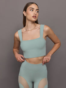 Model wears sage green bra top with a square neckline and wide shoulder straps.
