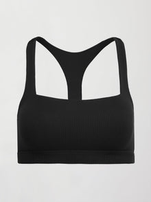 Model wears a black, ribbed, racerback sports bra with a smooth, sculpting fit.
