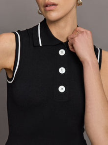 Model wears a sleeveless black tennis polo with three white buttons. 