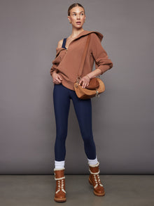 Styled outfit: navy jumpsuit layered with brown zip sweater, boots, and bag.