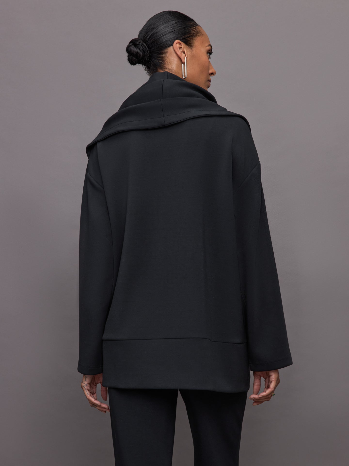 Model wears black open-front cardigan with a loose, draped fit, wide bell sleeves, and side pockets.