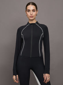 Model wears a black mock neck long sleeve top with thumb holes with thin white stripes outlining a corseted physique.