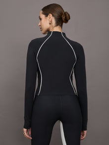Model wears a black mock neck long sleeve top with thumb holes with thin white stripes outlining a corseted physique.
