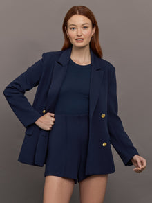 Model wears the Navy double-breasted blazer in Scuba, with a tailored fit, and a smooth, contoured finish.