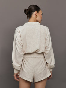 Model wears lightweight windbreaker with a snow leopard print, front zipper, and collared neck.
