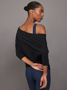 Back view of model wearing Long Sleeve Off Shoulder Tee Black showing draped fit.