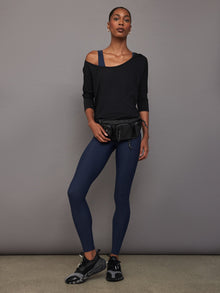 Full body view of model styled in Long Sleeve Off Shoulder Tee Black with navy leggings and sneakers.