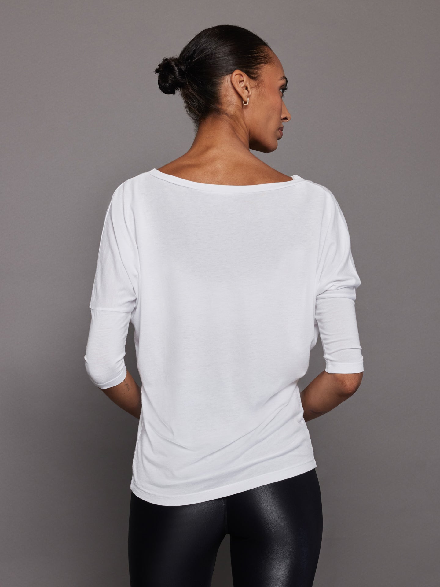 Back view of white off-shoulder tee with relaxed silhouette on model.